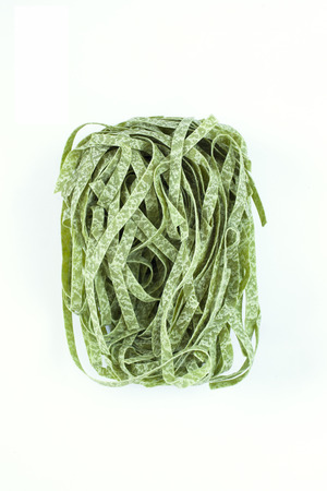 Dry pasta spinach tagliatelle, fettuccine single nest isolated on white backgroundの写真素材