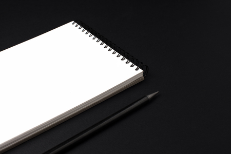 Opened clean notebook or sketchbook with pencil on black backgroundの写真素材
