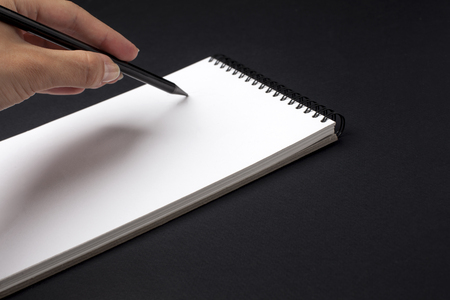Human hand with pencil prepare to writing on notebook. Black background.の写真素材