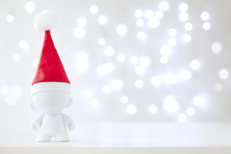 Christmas cute toy in Red Hat Santa Claus, Symbol New Year, Defocused Lights White Backgroundの写真素材