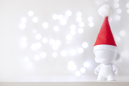 Christmas cute toy in Red Hat Santa Claus, Symbol New Year, Defocused Lights White Backgroundの写真素材