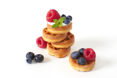 Pile of Belgian waffle with blueberry, raspberries and fresh mint on white background Isolatedの写真素材