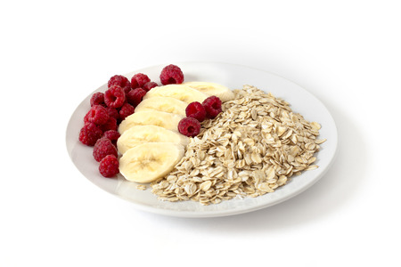 Breakfast of oatmeal with berries and bananas on white backgroundの写真素材