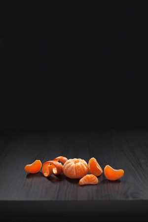 Christmas composition. Mandarins, tangerine slices, tangerine peel on black background. Christmas, winter, new year, halloween concept. Copy space.の写真素材