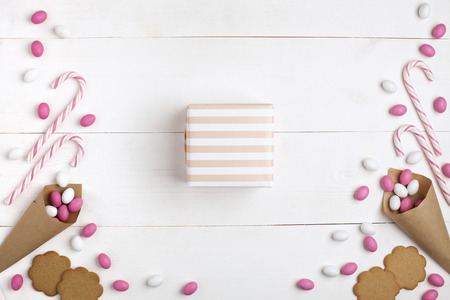 Frame colorful candies, striped lollipops, cookies, and present in the center. Top view, white wooden background. Valentines Dayの写真素材