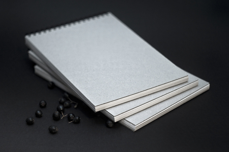 Several sketchbooks with a hard cardboard cover on a black background.の写真素材