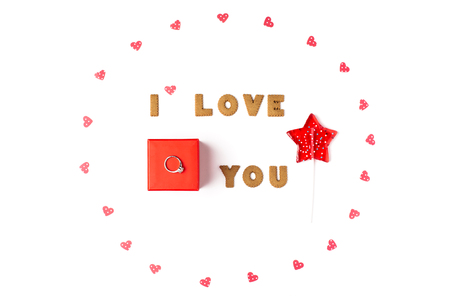 Valentine's day concept. Declaration of love, frame made of paper hearts, lollipop in form star. In the center red gift box with ring. Flat lay, top view, white background, isolated, copy spaceの写真素材