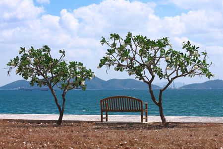 A view of Sichang Island in Thailand,with plumeria trees and chair provided for sitting to relax. There are many kind of boat around this island, such as fishing boat, cargo ship,barge ,etc.の写真素材