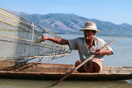 INLE LAKE, MYANMAR - FEBRUARY 16: Fisherman catches fish for food on February 16, 2011 on Inle Lake, Myanmar. Intha people possess the leg-rowing style and the unique coop-like fishing equipmentのeditorial素材