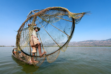 INLE LAKE, MYANMAR - FEBRUARY 16: Fisherman catches fish for food on February 16, 2011 on Inle Lake, Myanmar. Intha people possess the leg-rowing style and the unique coop-like fishing equipmentのeditorial素材