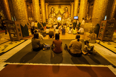 YANGON, MYANMAR - FEBRUARY 13: unidentified burmese people sitting in front of buddha image at Shwedagon Pagada on February 13, 2011 in Yangon, Myanmar.のeditorial素材