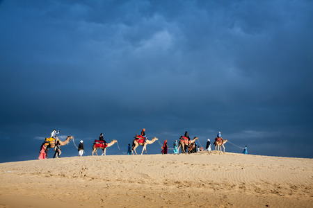JAISALMER, INDIA - FEB 26: Cameleer and customers at the Sam Sand Dune on Feb 26, 2013 in Jaisalmer, India. Apart from farming, camel riding activity is another income source for desert villagersのeditorial素材