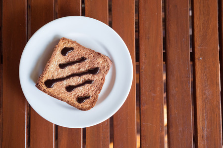Chocolate Spread on Toast in white disk on wood table window lightの写真素材