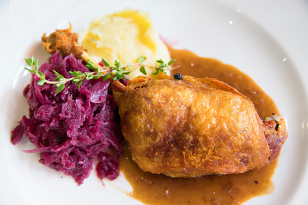 Duck confit with purple cabbage and mashed potato on white plateの写真素材