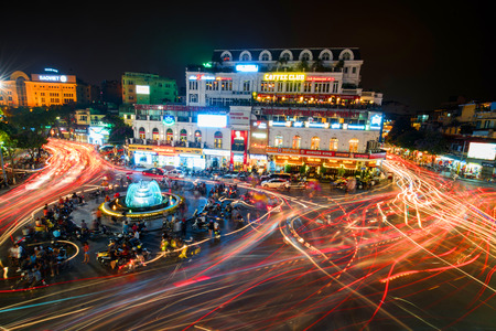 HANOI, VIETNAM - MAY 21, 2016: People and vehicles light trails crowd on busy intersection locating...