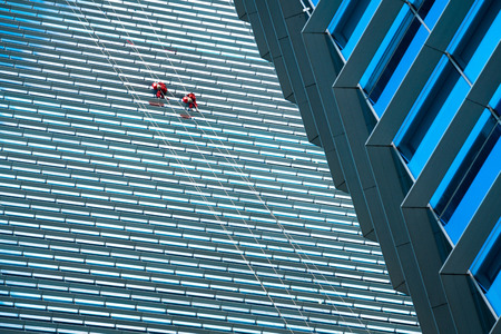 group of workers cleaning windows service on high rise building, wide shot