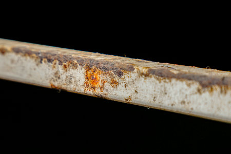 Close-up of a weathered and rusty metal beam against a stark black background, showcasing the effects of corrosion and decay.の写真素材