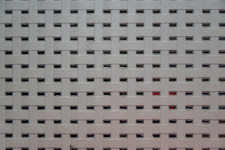 Close-up of a white woven plastic surface with a red accent, showcasing texture and pattern, perfect for backgrounds and design elements.の写真素材