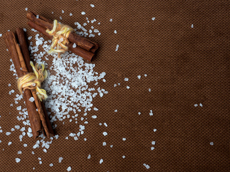 Cinnamon sticks tied with string. A scattering of sea salt around. On a nice brown background with a place for the inscription on the right.の写真素材