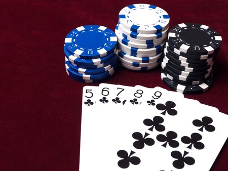 The assembled combination of flush in poker on red cloth with chips of different value. Strong cards to win a big jackpot.の写真素材