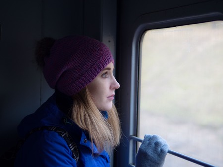 A young girl is traveling on a train. Her looks expectantly out the window.の写真素材