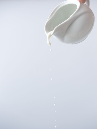 From the creamer drop the last drops of milk. White background and frost drops.の写真素材