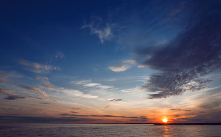 Beautiful sunset over the water. Air clouds of different colors.の写真素材