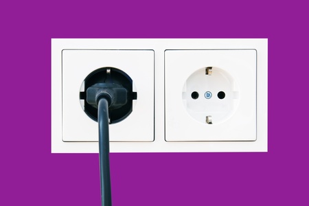Electrical outlet with plug on pink painted wallの写真素材