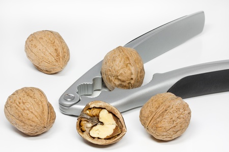 Walnuts with nut cracker on white background