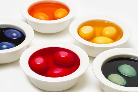 Painting easter eggs with liquid colour in white bowlsの写真素材