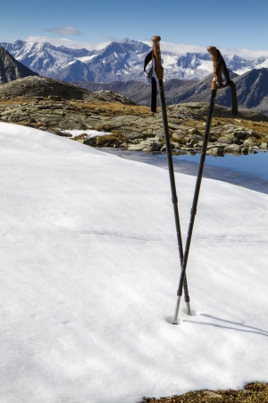 A pair of walking sticks in snow and mountainsの写真素材