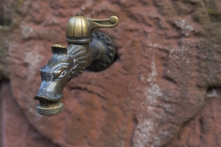 Old tap mounted on a sandstone wallの写真素材