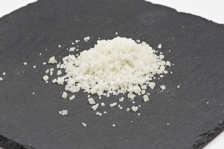 Heap of coarse sea salt on a black stone surfaceの写真素材