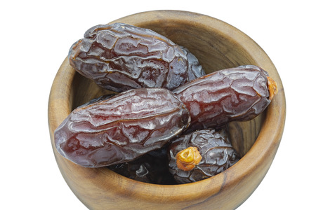 Dried dates in a wooden bowl isolated on white