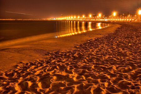 Sandy beach at night and lanterns in the distance.の写真素材