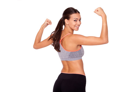 In love with sport. A young beautiful woman in gym clothes flexing her arms against white isolated background.の写真素材