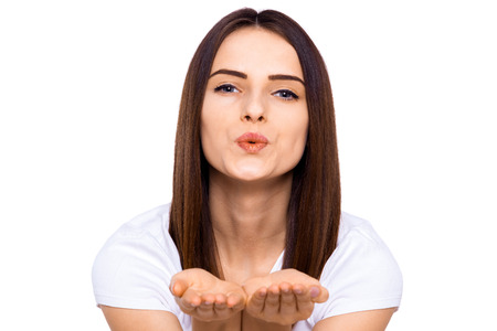 Flirting beauty. Beautiful young woman in shirt sending a kiss at camera and holding copy space while standing against white backgroundの写真素材