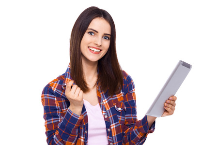 Technologies making life easier. Beautiful young woman holding digital tablet and looking at camera with smile while standing against white backgroundの写真素材