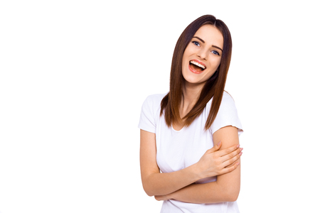 Laughs are fun. Portrait of a beautiful young woman laughing while standing against a white wallの写真素材