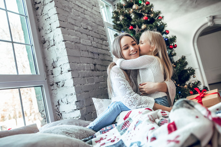 Happy family mother and child daughter on Christmas morning at the Christmas tree with gifts. family, holidays and happiness concepの写真素材