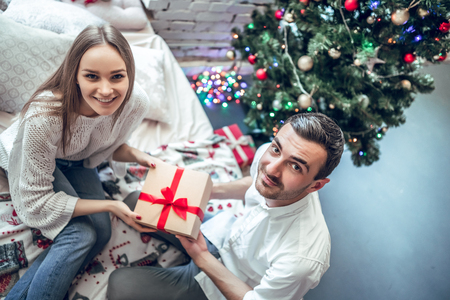 Man give present gift box woman. Christmas holiday. Happy couple sitting on bed. Top Viewの写真素材
