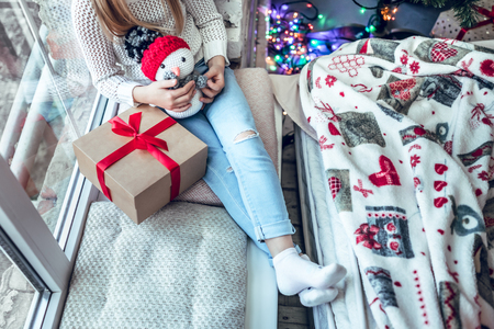 No face. Child little girl sitting by the window with a snowman. Top viewの写真素材