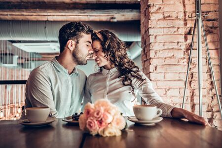 Joyful moments.Beautiful couple in love hugging each other sitting in restaurant.の写真素材