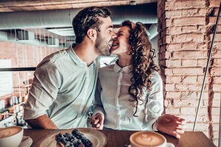 Cheerful mood. A couple in love is enjoying each other while sitting in a cafe.