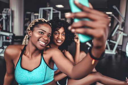 Two smiling beautiful girls in the gym do selfie. Sports, fitness, boxing, gym.の写真素材