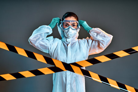 Doctor, nurse show how to wearing protection suit for fighting Covid-19 coronavirus with dark background isolated. Medical worker in full protective gearの写真素材