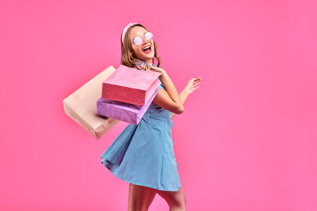 Shopping woman happy smiling holding shopping bags isolated on pink background. Copy spaceの写真素材