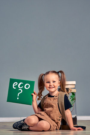 Little girl have terrarium jar with plant isolated on gray. Eco sign. Ecology concept. Vertical photo. Copy spaceの写真素材