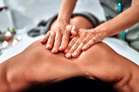 Close-up view masseur hands doing spin massage. Selective focusの写真素材