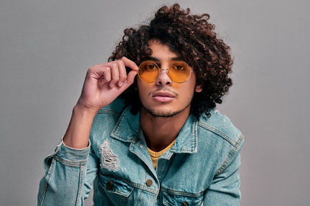 Portrait of calm sexy young arabian man adjusting eyeglasses. Cool eastern smart student on isolated...